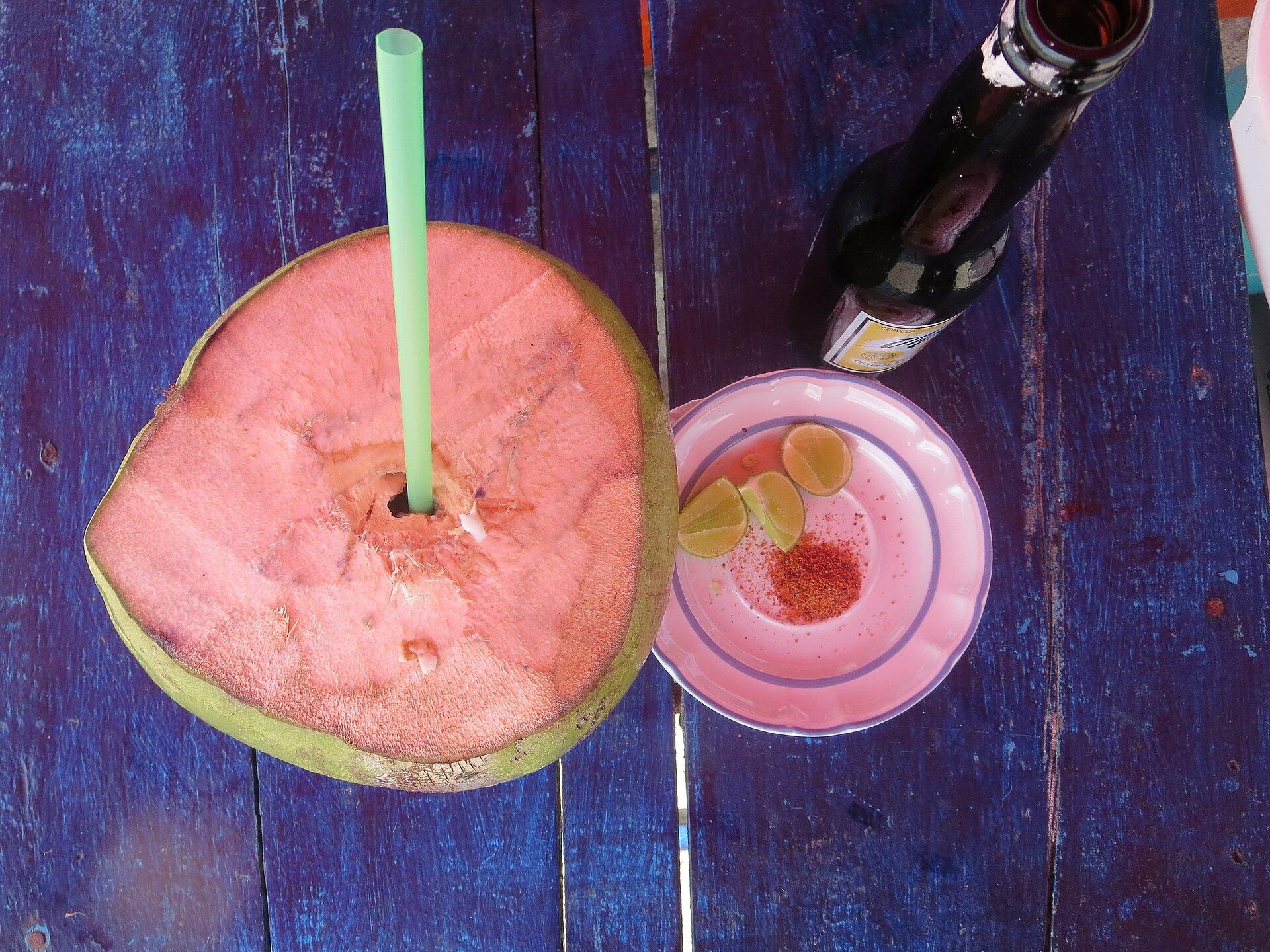 Coco tropical y fruta junto a una bebida en Puerto Escondido